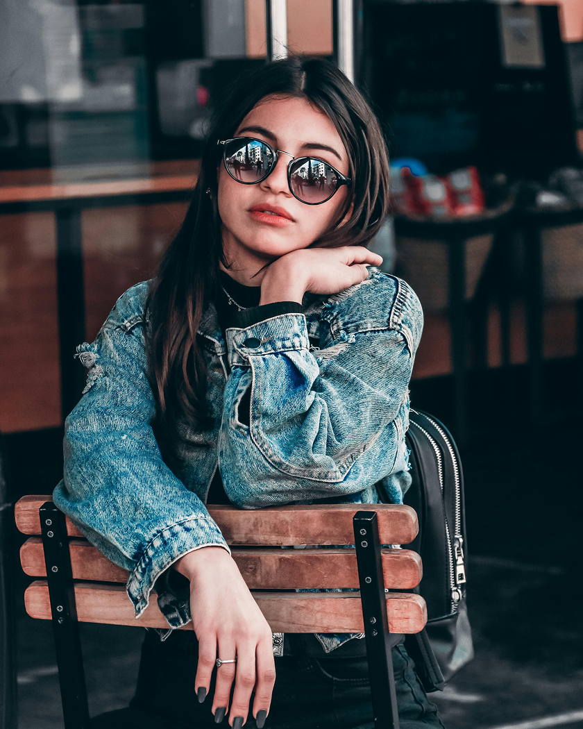 Woman wearing a casual denim jacket and sunglasses at a café — virtual try-on streetwear outfit